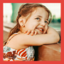 Little girl smiling with her head on a banister. White girl. Red hair. Hawaiian dress.